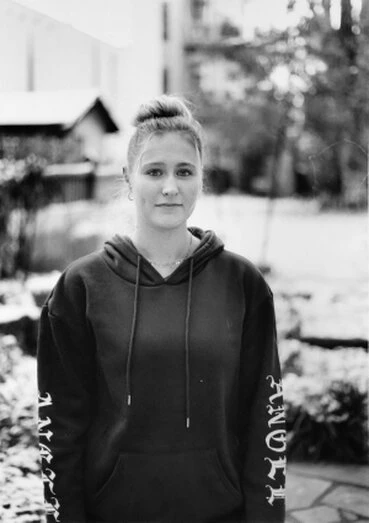 eine junge Frau mit hochgebundenen Haaren und dunklem Kaputzenpulli